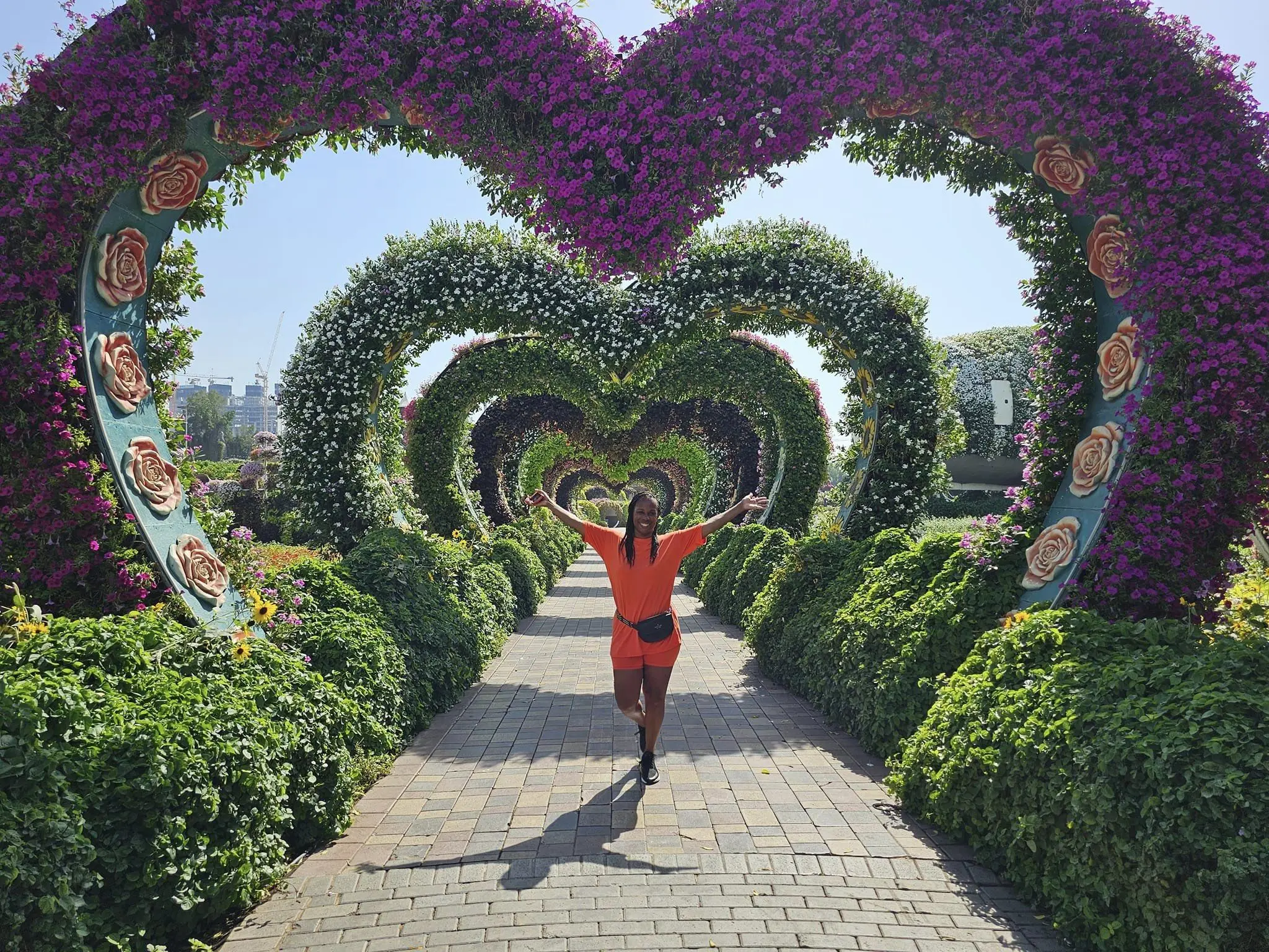 malindagarden (1) Person walking under a heart-shaped floral archway in a garden.